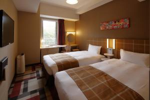 um quarto de hotel com duas camas e uma televisão em Hotel Monte Hermana Kobe Amalie em Kobe