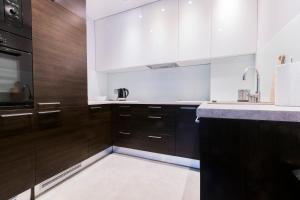 a kitchen with wooden cabinets and a sink at Pohulanka Luxury in Gdańsk