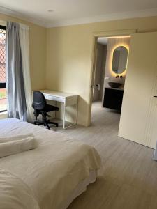 a bedroom with a bed and a desk and a chair at Maisie Haven in Brisbane