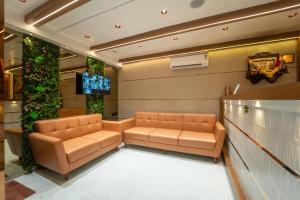 a waiting room with two leather couches and a tv at Hotel Royal Inn in Thane