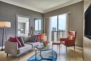 a living room with a couch and two chairs at Grand Copthorne Waterfront Hotel Singapore in Singapore