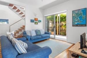 a living room with two blue couches and a tv at Hyams Reflections Hyams Beach in Hyams Beach