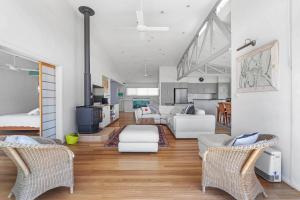 a living room with white furniture and a kitchen at Hyams Reflections Hyams Beach in Hyams Beach