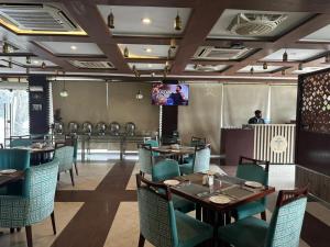 a dining room with tables and chairs and a tv at City Oasis Boutique Hotel in Lahore