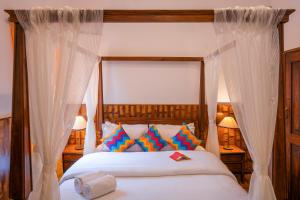 a bedroom with a canopy bed with white curtains at goSTOPS Ooty in Ooty +68 photos