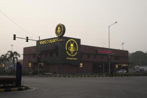 a building with a sign in front of a parking lot at Round D Clock, IGI Airport in New Delhi