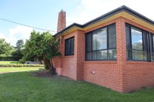 a red brick house with a tree in the yard at Spacious 3-Bed Home in Central Tenterfield in Tenterfield