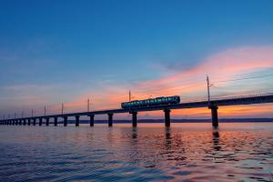 a train on a bridge over the water at sunset at KAMENOI HOTEL Itako in Itako