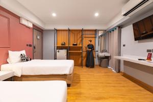 a woman standing in a room with two beds at Lima Hotel in Phra Nakhon Si Ayutthaya