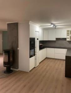 a kitchen with white cabinets and a tv in a room at Gardermoen Airport, 5Min in Sand