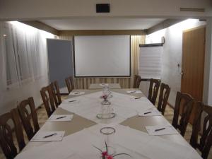 een vergaderzaal met een lange tafel met stoelen en een scherm bij Hotel Kaiserquelle in Salzgitter