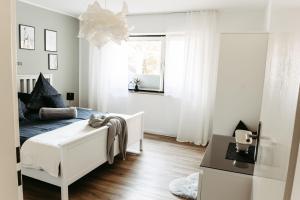 a white bedroom with a bed and a window at HOME AM SEE Ferienwohnung in Möhnesee