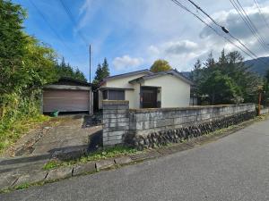 a house with a stone wall next to a street at ほしのすみか in Nikko