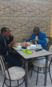 tres hombres sentados en una mesa comiendo comida en Hotel Villamar, en Quito