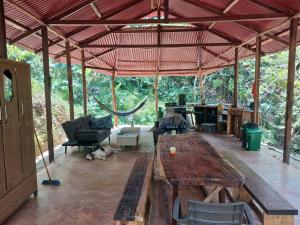 a large pavilion with a wooden table and a hammock at Private jungle accommodation with waterfall in Minca