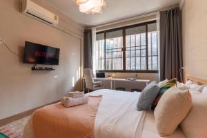 ein Schlafzimmer mit Bett, Schreibtisch und Fenster in der Unterkunft Walk2BTS, KingBed, FastWiFi, FreeLaundry, Netflix in Klong Toi