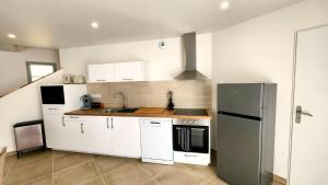 a kitchen with white cabinets and a stainless steel refrigerator at La maison des Vignes est climatisée avec ménage, draps et serviettes inclus in Tabanac