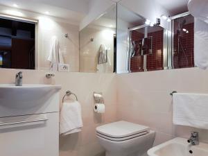 a white bathroom with a toilet and a sink at Aretusa Apartments in Siracusa