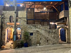 an old stone building with wooden shutters on it at לומינוס הגפן in Ḥurfeish