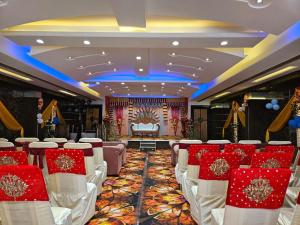 a ballroom with white chairs and a stage in the background at Hotel MNG The Platinum in Kānpur