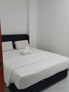 a white bed with a black headboard and white sheets at H Sri Sayang Hotel Sdn Bhd in Skudai