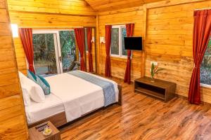 a bedroom with a bed and a flat screen tv at Nature Trails Rock Valley, Goa in Ponda