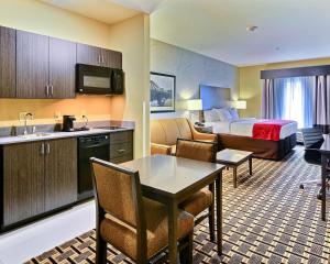 a hotel room with a king bed and a kitchen at Comfort Suites Uniontown in Uniontown