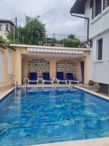 a large swimming pool with blue chairs and a building at Guest House Harmony in Veliko Tŭrnovo