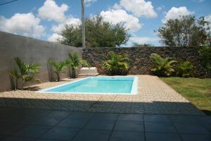 a swimming pool in a garden with a stone wall at Happy Villa in Trou aux Biches