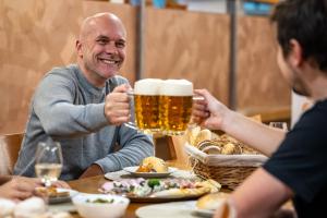 a man sitting at a table with a mug of beer at Hotel Opava - free parking in Opava
