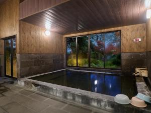 a swimming pool in a room with a large window at Chikurakutei in Minami Aso