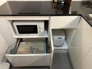 a white cabinet with a microwave in a kitchen at Tree House in Ban Rangeng +9 photos