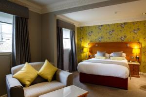 um quarto de hotel com uma cama e um sofá em Best Western Lichfield City Centre The George Hotel em Lichfield