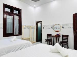 a bedroom with two beds and a table and chairs at Nutty Village Phu Quoc in Phú Quốc