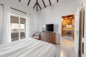 a bedroom with a bed and a tv and a kitchen at Benny Fañabé - 2 Bed and Loft Apartment, AC, Pool & Parking in Adeje