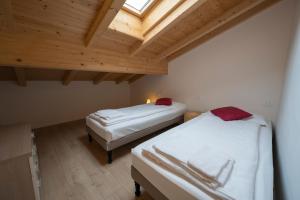 two beds in a room with a wooden ceiling at Appartamento Bastione in Riva del Garda