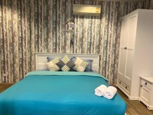 a bedroom with a blue bed with two towels at Rain cha-am by J in Cha Am +19 photos
