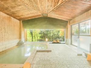 ein Swimmingpool in einem Raum mit einem großen Fenster in der Unterkunft Kirishima Momijidani Seiryuso in Kirishima