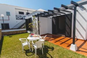 a patio with a table and chairs under a pergola at Los Cardones Boutique Village in Playa de las Americas