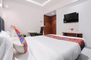 a bedroom with a white bed and a flat screen tv at FabHotel Suruchi Homes in Vasai
