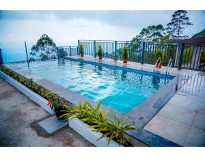 a large swimming pool with blue water in a yard at Clouds end Resorts Munnar in Jāmb