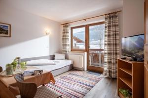 a living room with a bed and a large window at Gästehaus Wildauer in Ebbs
