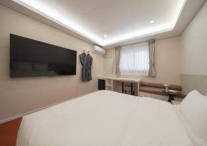 a bedroom with a large white bed and a flat screen tv at No 25 Iksan Station Branch in Iksan