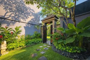 a garden with a door and some plants at Seminyak Icon - by Karaniya Experience - CHSE certified in Seminyak