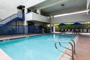 a large swimming pool with chairs and umbrellas at Quality Inn & Suites Los Angeles Airport - Stadium District in Inglewood