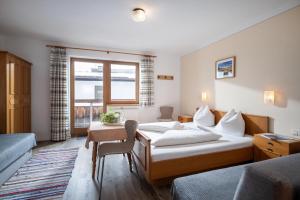 a bedroom with a bed and a table and a window at Gästehaus Wildauer in Ebbs