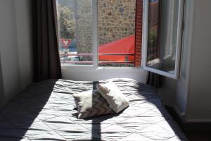- un lit avec un oreiller dans une chambre avec une fenêtre dans l'établissement Cottage de Noëlle, à Limoges