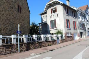 Ein weißes Gebäude mit einem Zaun an der Straßenseite. in der Unterkunft Cottage de Noëlle in Limoges