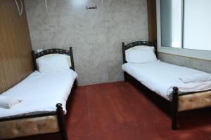 two twin beds in a room with a window at נוף הכפר - 6 חדרי אירוח לזוגות ומשפחות עם ג'קוזי ובריכה מחוממת משותפים במתחם in Buq‘ātā +7 photos