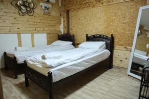 two beds in a room with wooden walls at נוף הכפר - 6 חדרי אירוח לזוגות ומשפחות עם ג'קוזי ובריכה מחוממת משותפים במתחם in Buq‘ātā